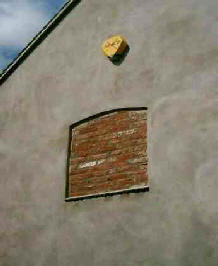 Burglar alarm above a bricked up window